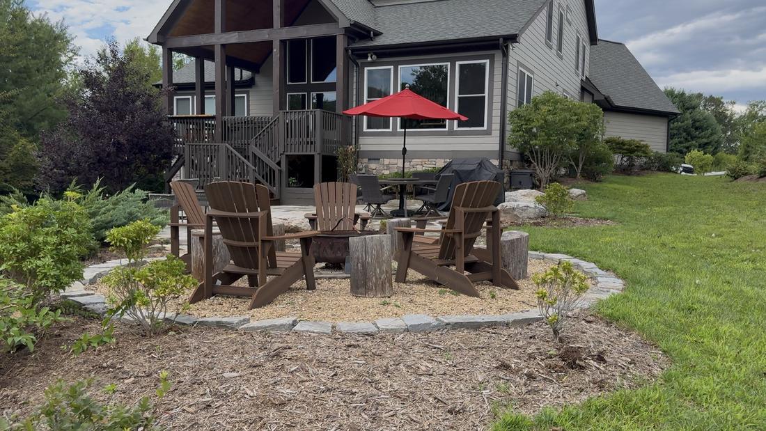 Firepit patio with adirondack chairs, trimmed shrub beds and fresh mulch behind a home